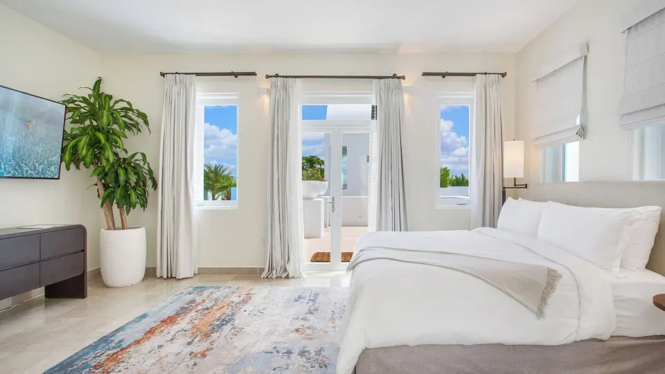 Five Bedroom Garden Villa bedroom with white bed and terrace doors at Aurora Anguilla Resort & Golf Club.