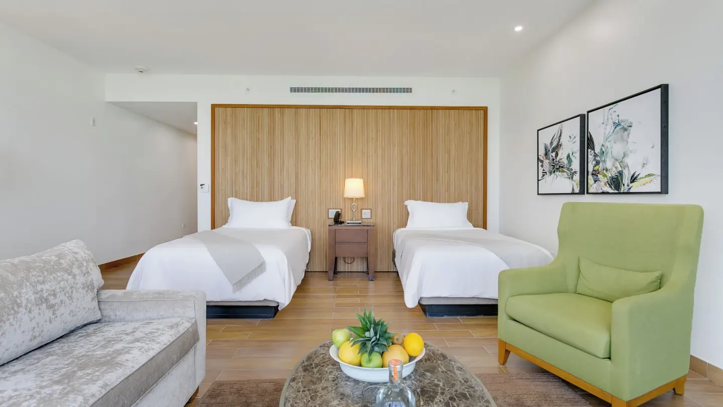 Island View Deluxe Room with two beds and green chair at Aurora Anguilla Resort & Golf Club.