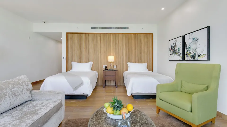 Island View Deluxe Room with two beds and green chair at Aurora Anguilla Resort & Golf Club.