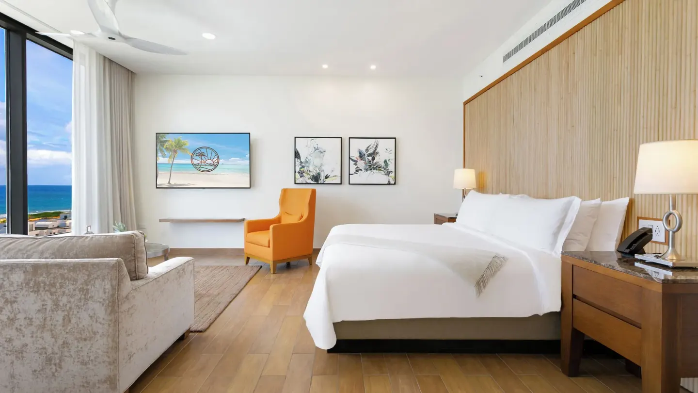 Ocean View Deluxe Room king bed and lounge seating at Aurora Anguilla Resort & Golf Club.