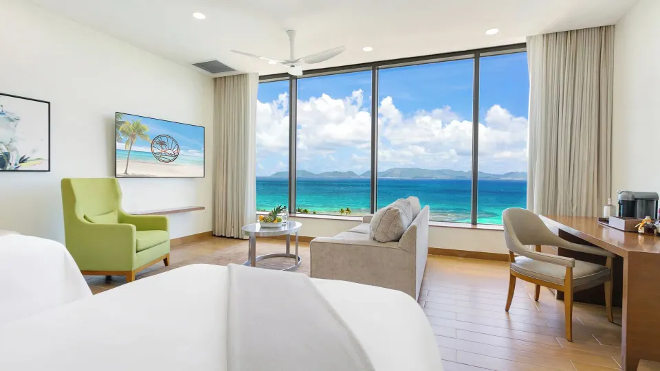 Ocean View Deluxe Room lounge area and king bed with sea view at Aurora Anguilla Resort & Golf Club.