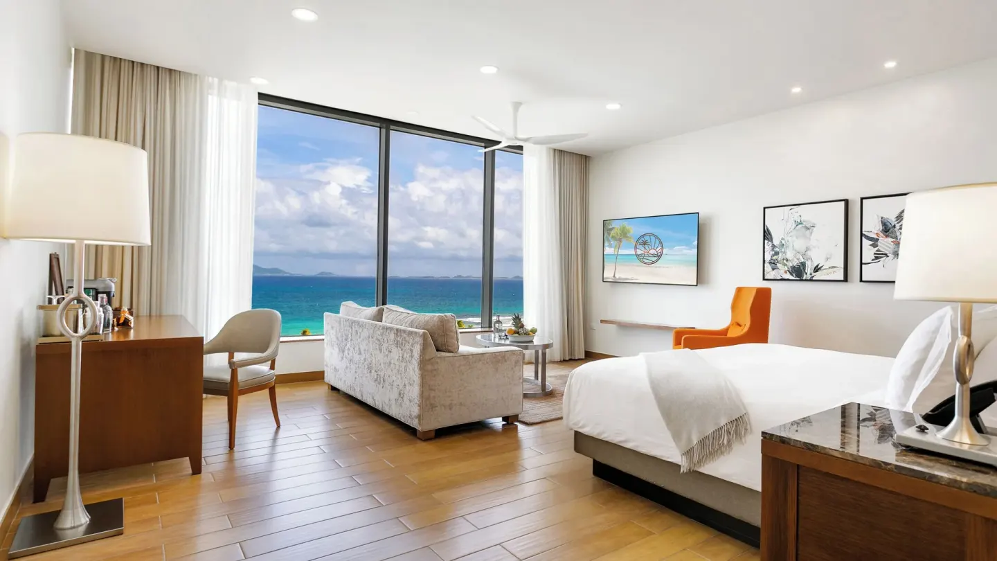 Ocean View Deluxe Room king bed with sofa and large sea window at Aurora Anguilla Resort & Golf Club.