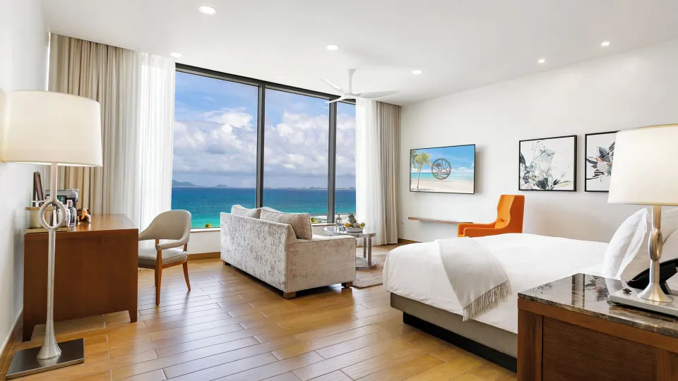 Ocean View Deluxe Room king bed with sofa and large sea window at Aurora Anguilla Resort & Golf Club.