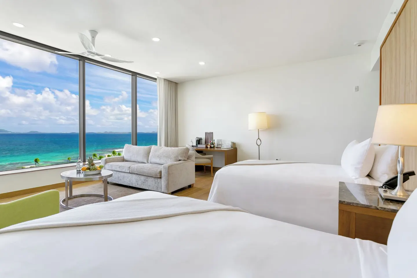 Ocean View Deluxe Room with two beds, sofa, and ocean windows at Aurora Anguilla Resort & Golf Club.