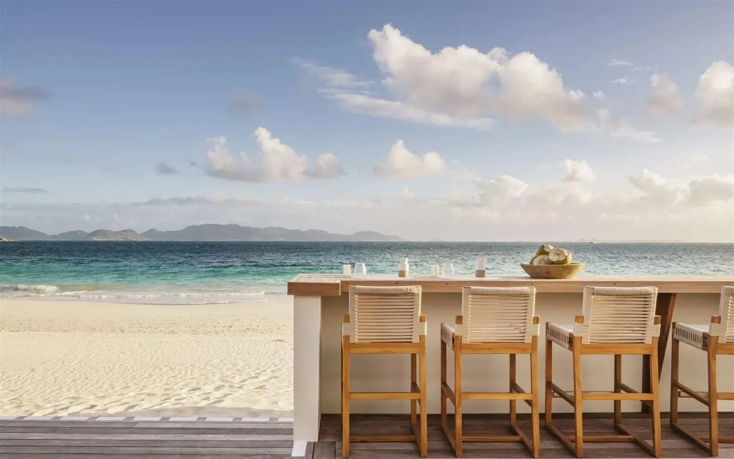 Beachfront terrace bar seating by the ocean at Aurora Anguilla Resort & Golf Club.