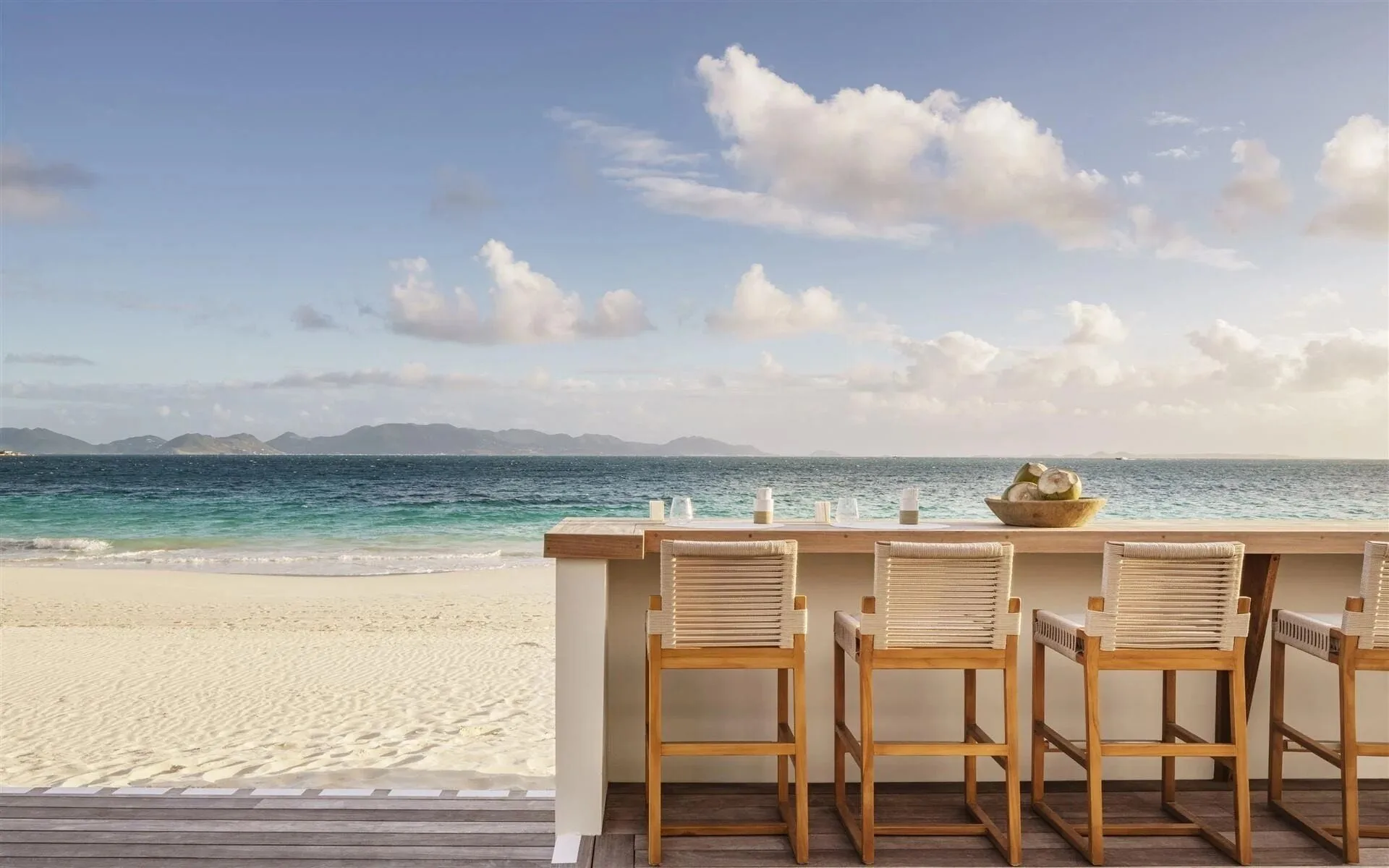 Beachfront terrace bar seating by the ocean at Aurora Anguilla Resort & Golf Club.