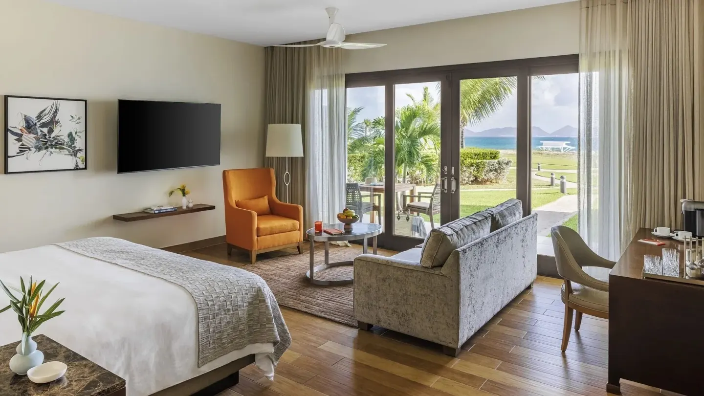 Oceanfront Junior Suite with king bed and garden patio view at Aurora Anguilla Resort & Golf Club.
