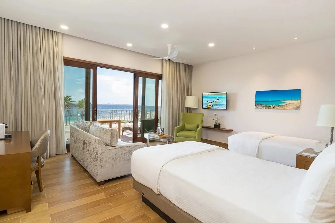 Oceanfront Junior Suite with two beds and balcony at Aurora Anguilla Resort & Golf Club.
