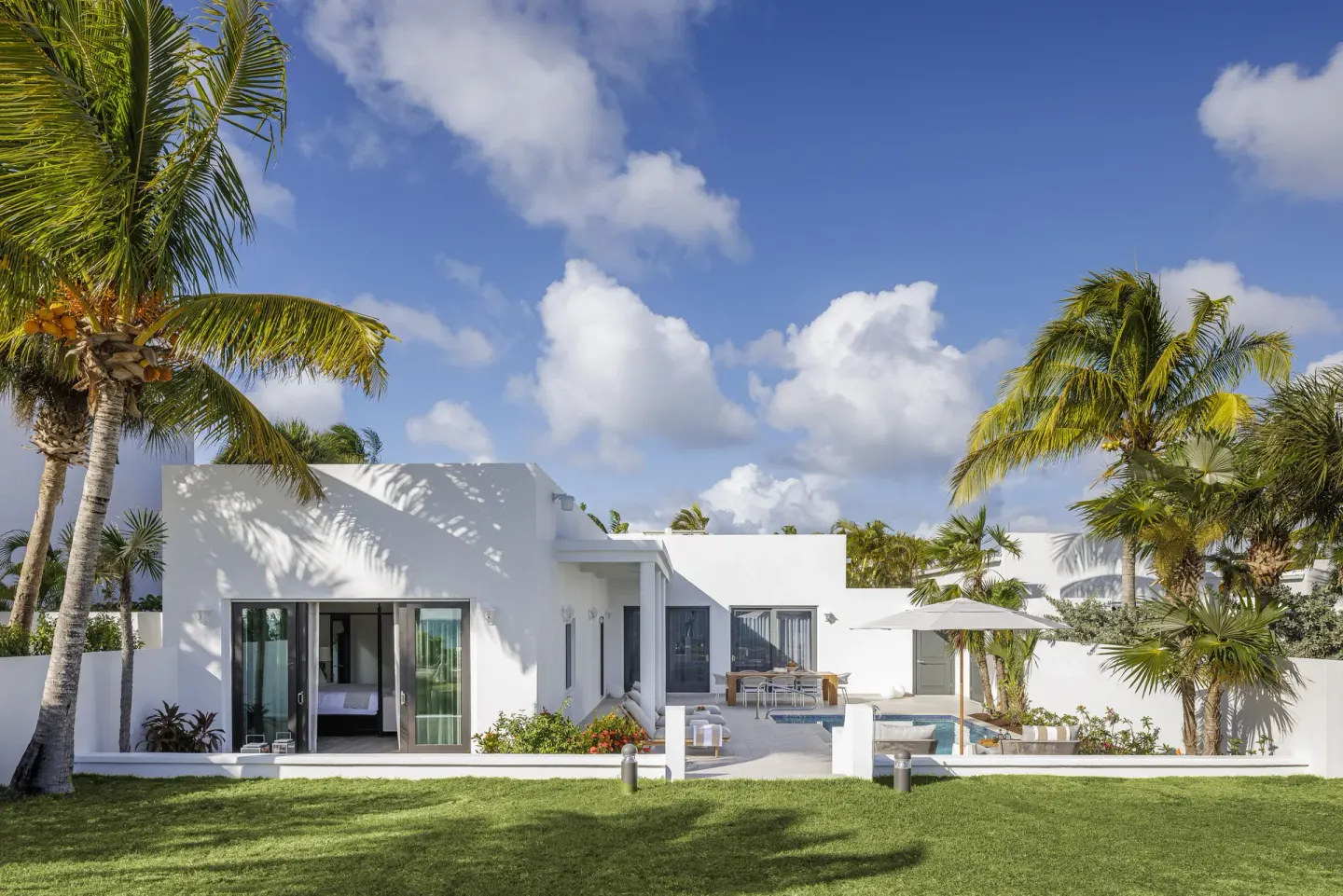 White beachfront villa exterior with palms at Aurora Anguilla Resort & Golf Club.