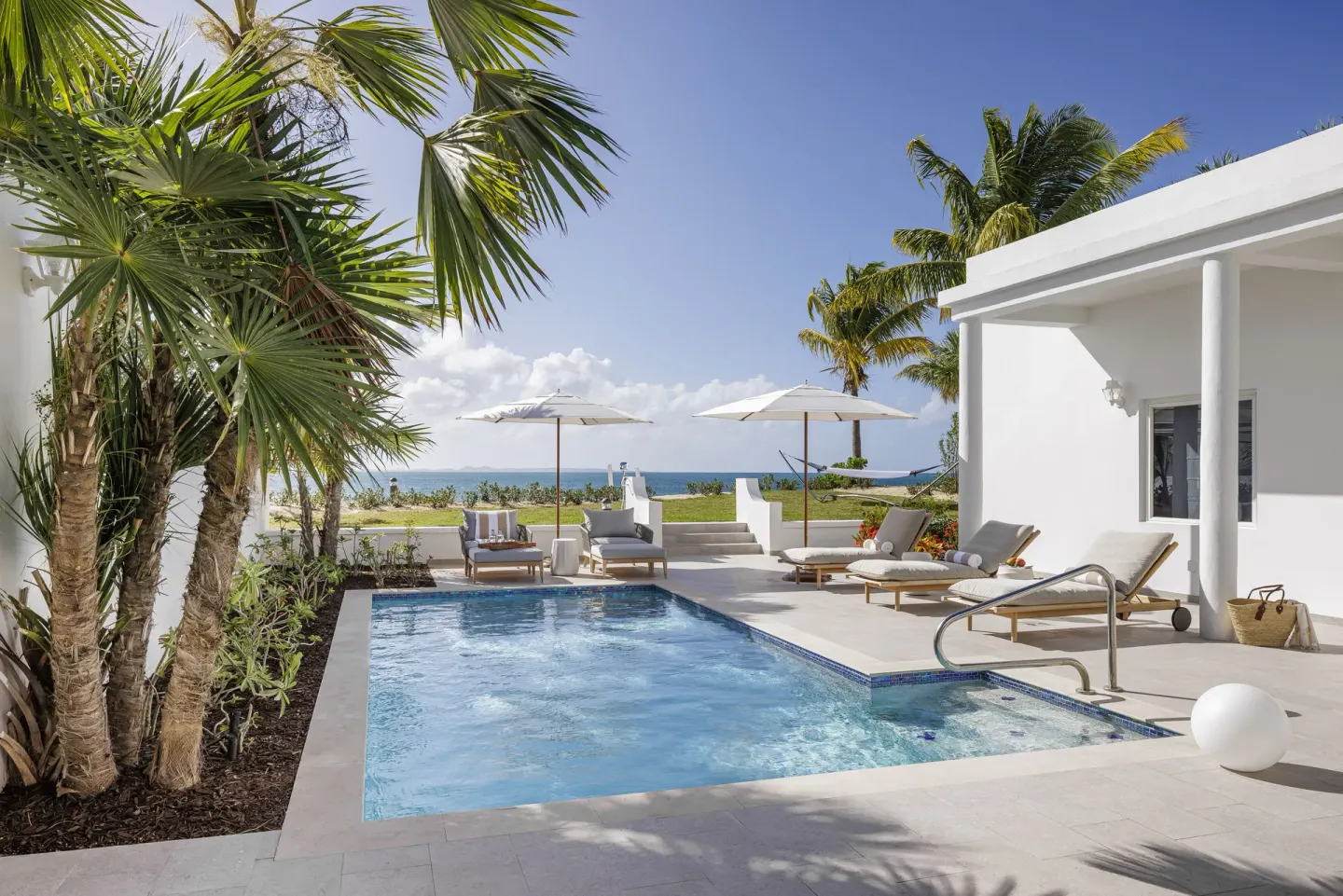 Private villa pool with loungers and ocean beyond at Aurora Anguilla Resort & Golf Club.
