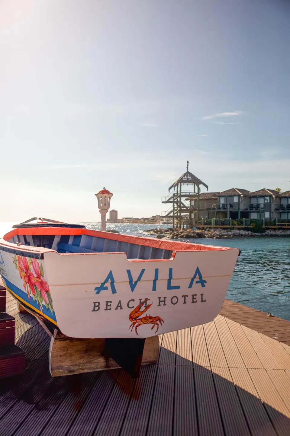 Painted Avila Beach Hotel boat on a dock beside the water.