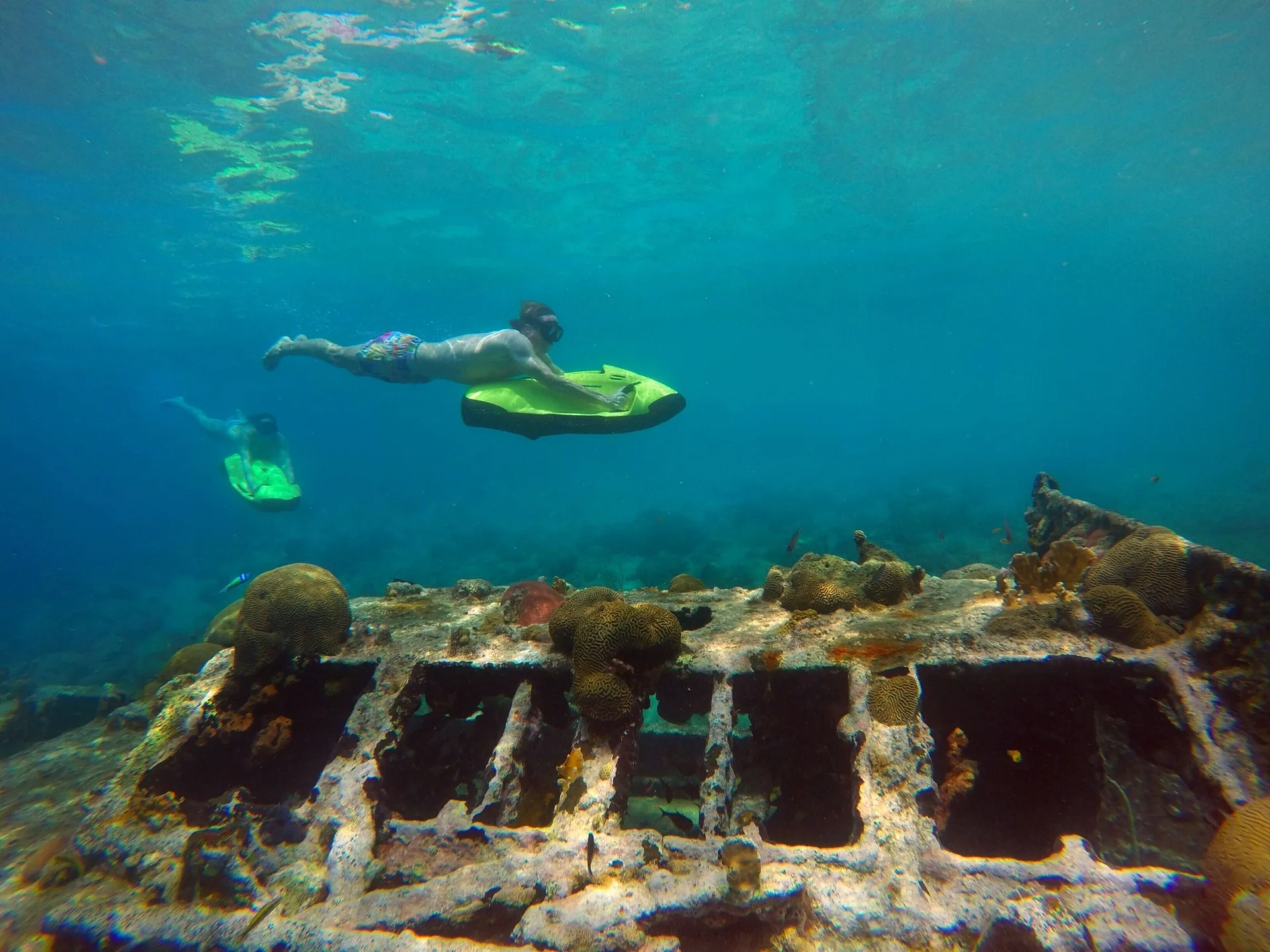 Snorkelers glide above a coral-covered wreck near Avila Beach Hotel.