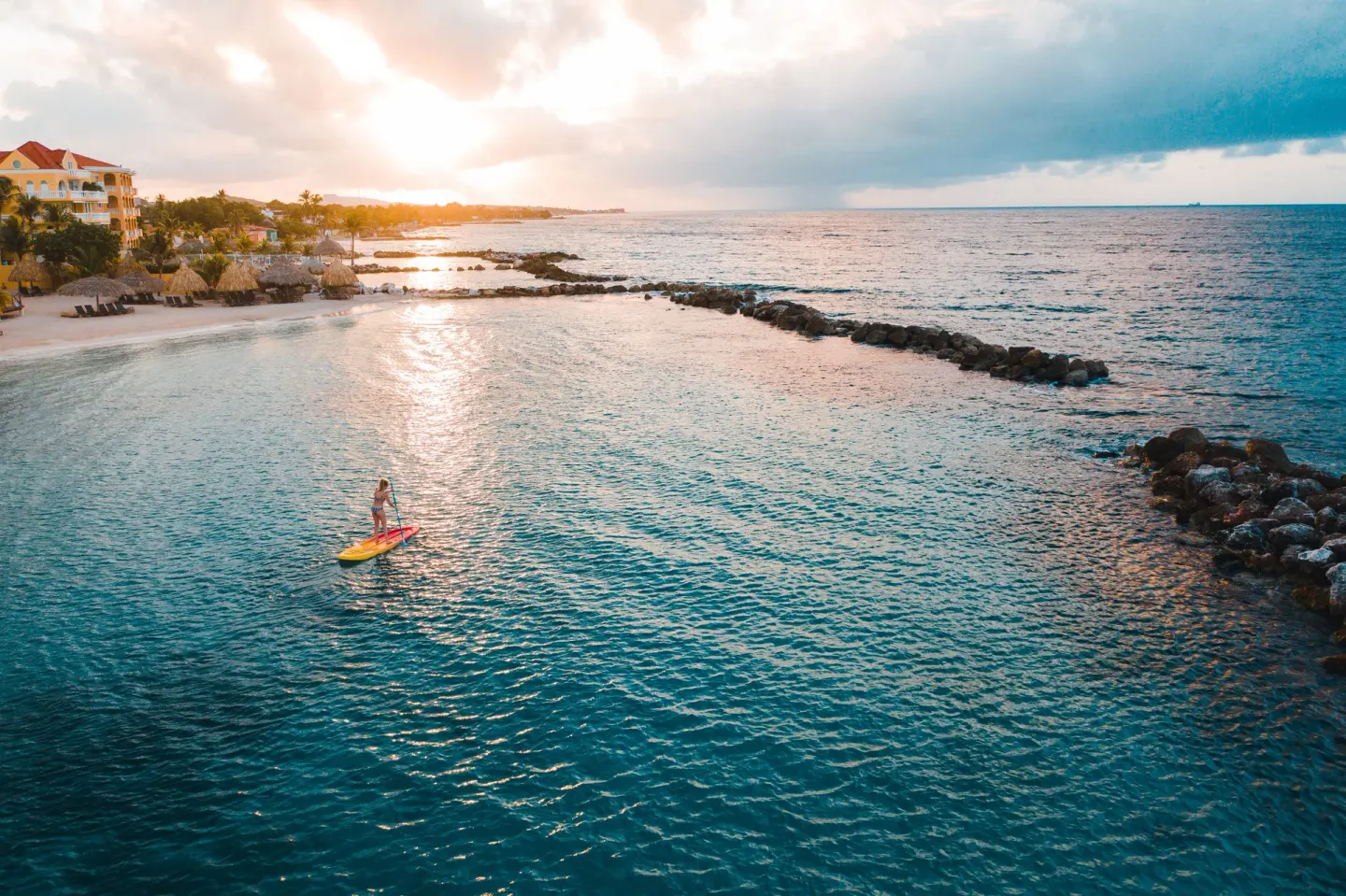 Paddleboarder on the calm shoreline at sunset by Avila Beach Hotel.