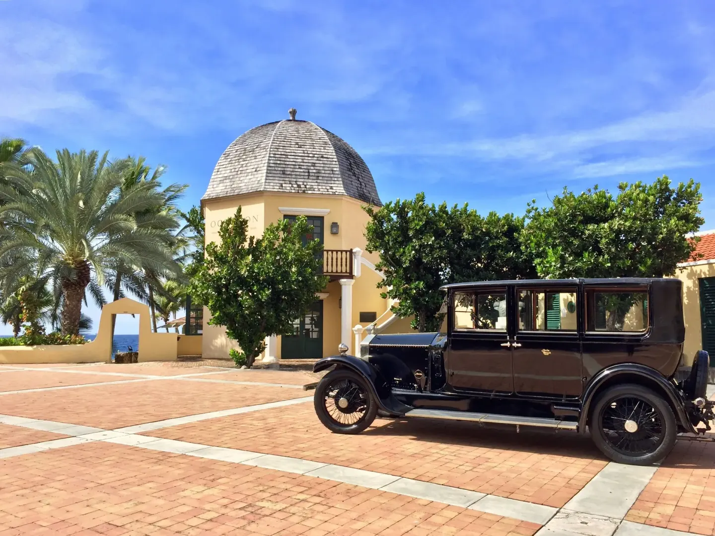 Vintage car parked by a domed yellow building at Avila Beach Hotel.
