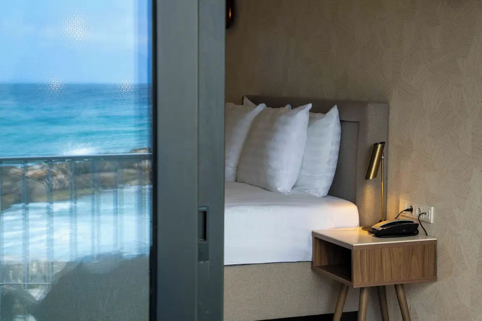 Deluxe Oceanfront bed and bedside table beside the sea view at Avila Beach Hotel.