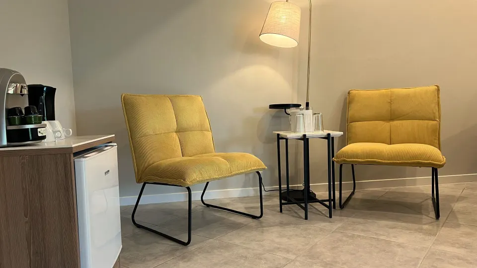 Deluxe Room seating area with yellow chairs and coffee station at Avila Beach Hotel.
