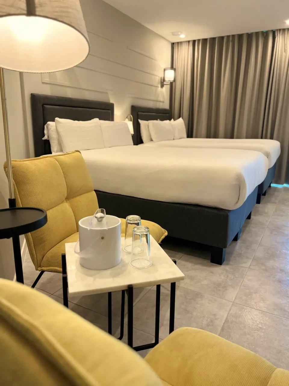 Deluxe Room with two beds, yellow chair, and tea setup at Avila Beach Hotel.