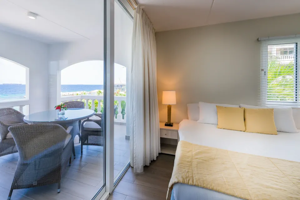 Bedroom and balcony of la Belle Alliance apartment at Avila Beach Hotel with ocean visible outside.