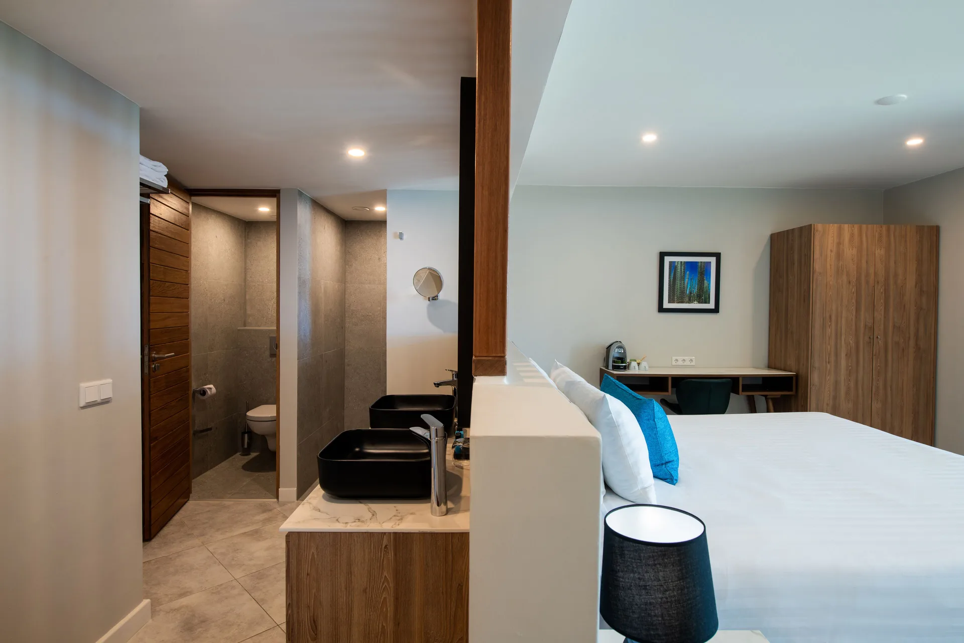 Preferred Room king bed beside open bathroom sinks and toilet area at Avila Beach Hotel.