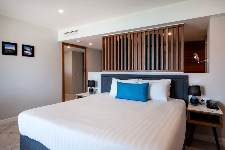Preferred Room king bed with blue pillow and wood slat headboard at Avila Beach Hotel.