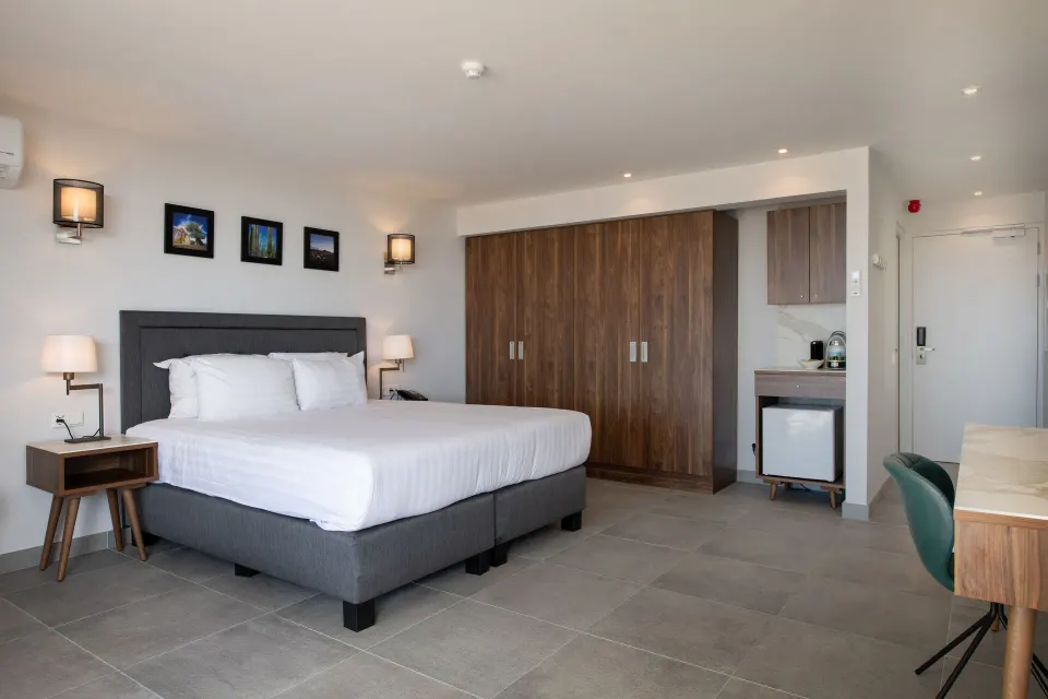 Premium apartment bedroom with bed, wardrobes, desk, and minibar at Avila Beach Hotel.