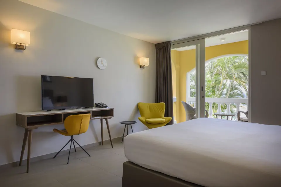 Standard Room with bed, desk, yellow chair and balcony at Avila Beach Hotel.