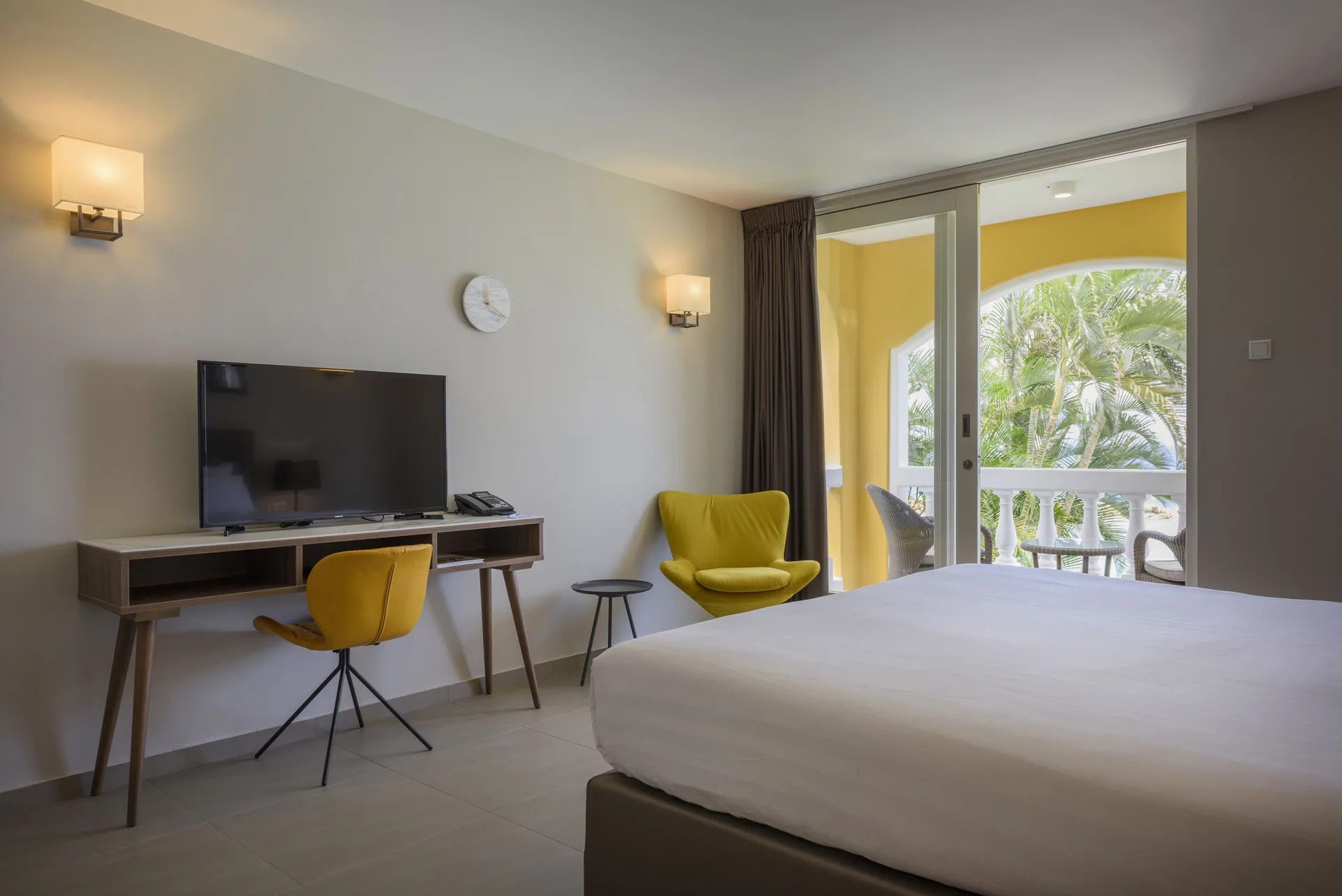 Standard Room with bed, desk, yellow chair and balcony at Avila Beach Hotel.