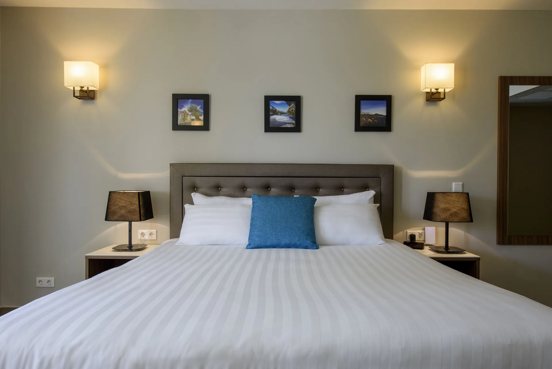 Standard Room king bed with blue pillow, bedside lamps and wall art at Avila Beach Hotel.
