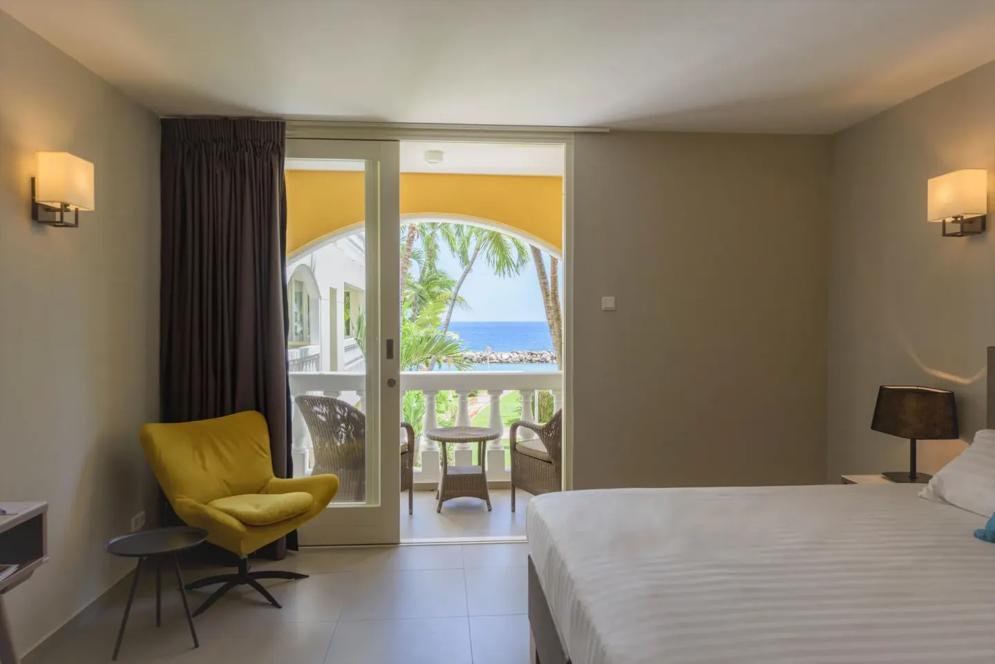 Standard Room with bed, yellow chair and balcony ocean view at Avila Beach Hotel.