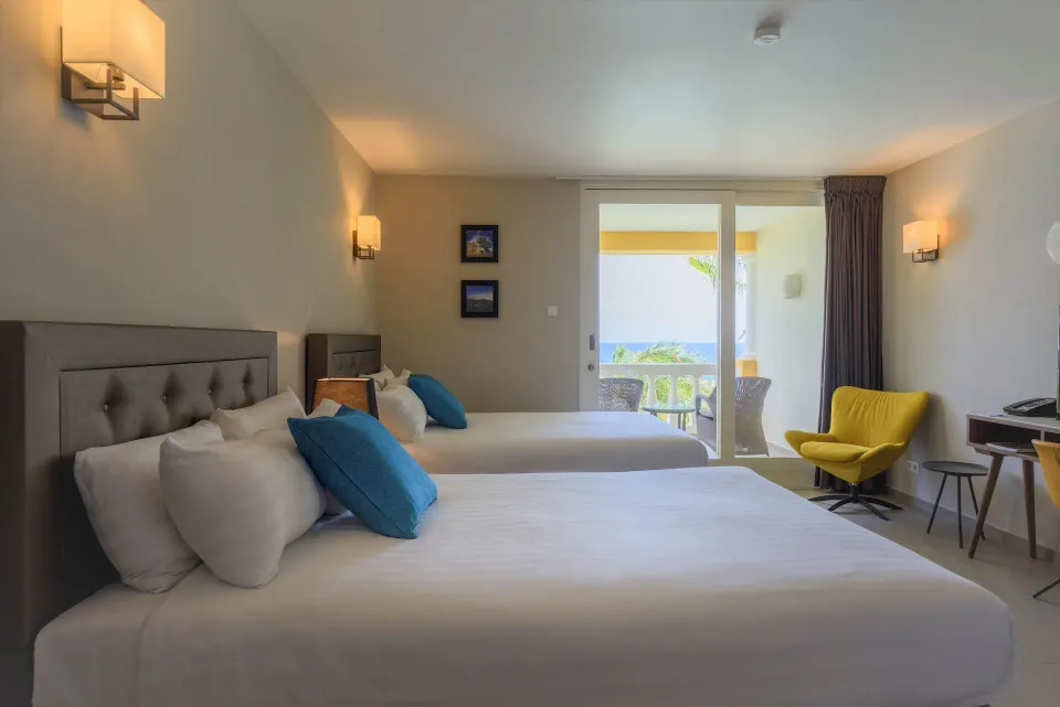 Standard Room twin beds with balcony doors and yellow chair at Avila Beach Hotel.