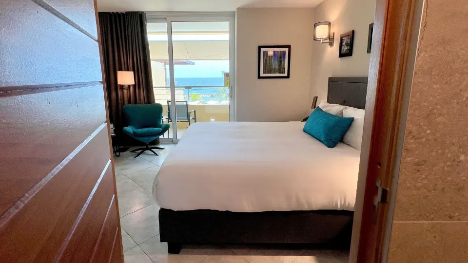 Standard Room king bed seen from the doorway with balcony beyond at Avila Beach Hotel.