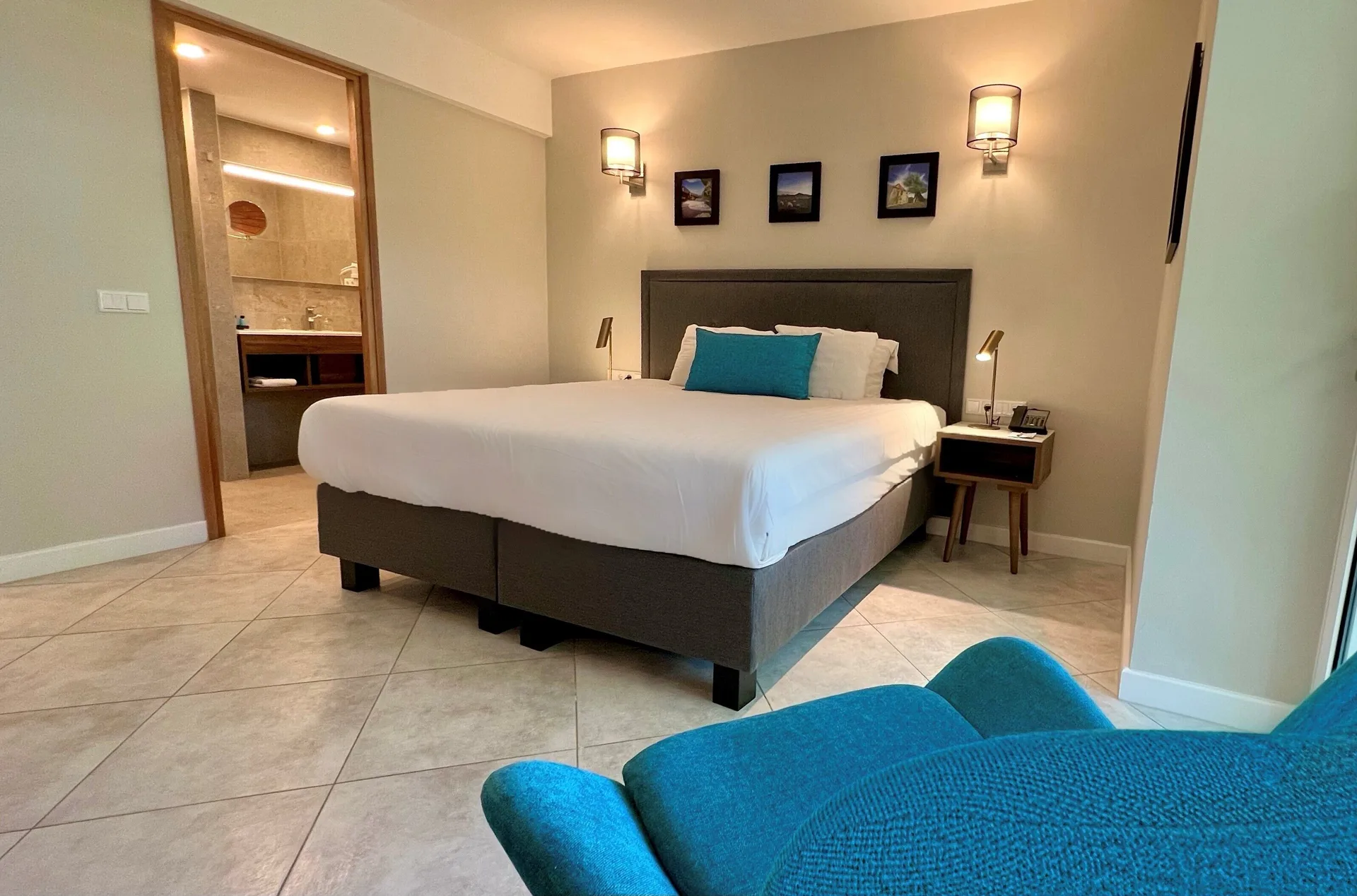 Standard Room king bed with teal chair and bathroom doorway at Avila Beach Hotel.