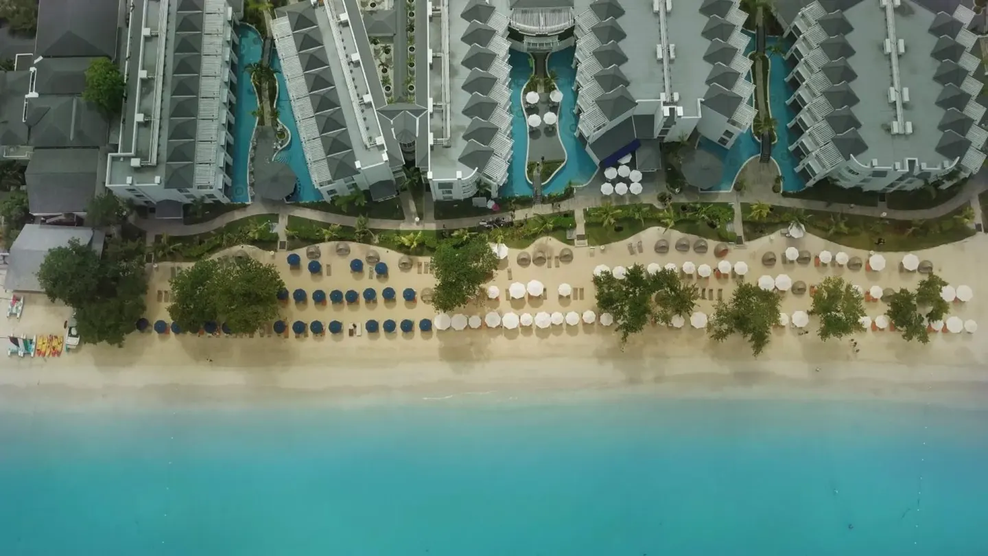Aerial view of the beachfront, loungers, pools, and resort buildings at Azul Beach Resort Negril.