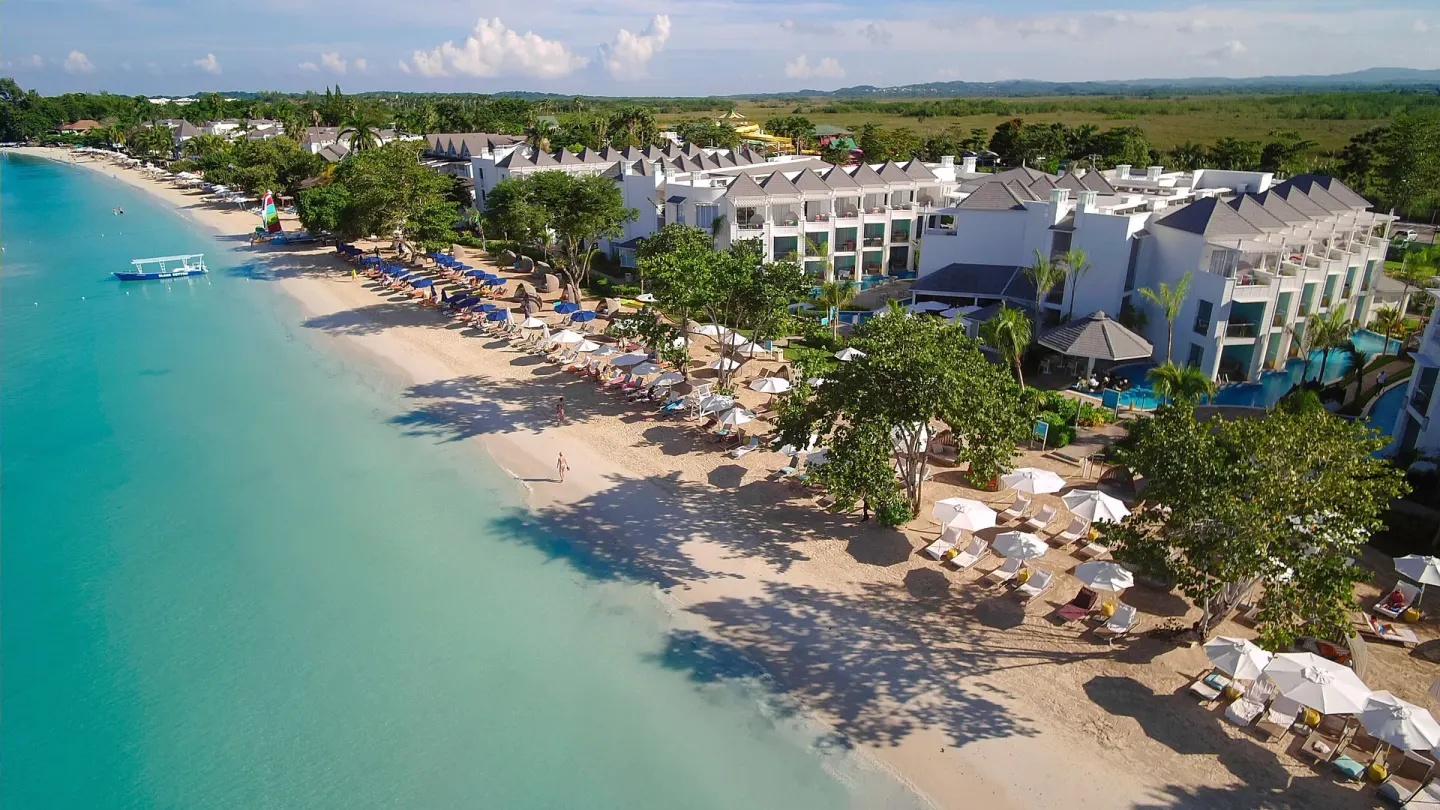 Aerial view of beach loungers, trees, and resort buildings at Azul Beach Resort Negril.