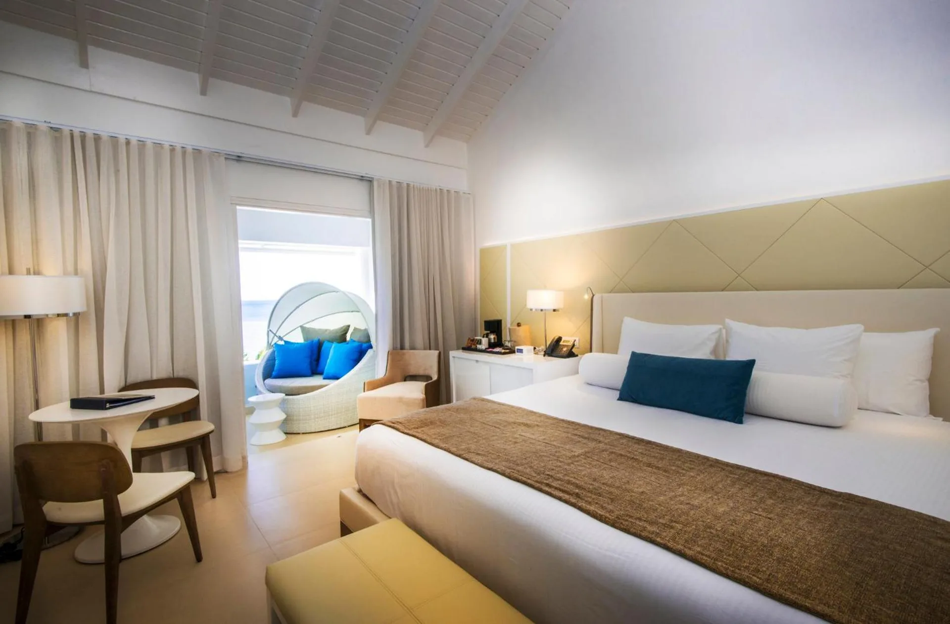 King bed guest room at Azul Beach Resort Negril with desk, seating and a balcony daybed outside.