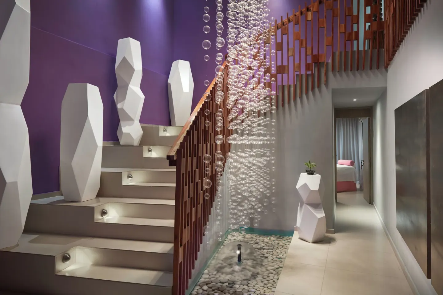 Lobby staircase with purple wall, sculptural decor, and hanging glass feature at Azul Beach Resort Negril.