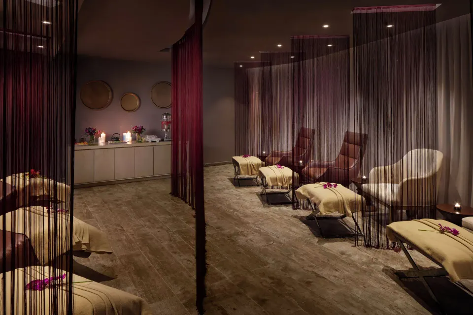 Spa relaxation room with loungers, curtains, candles, and flowers at Azul Beach Resort Negril.