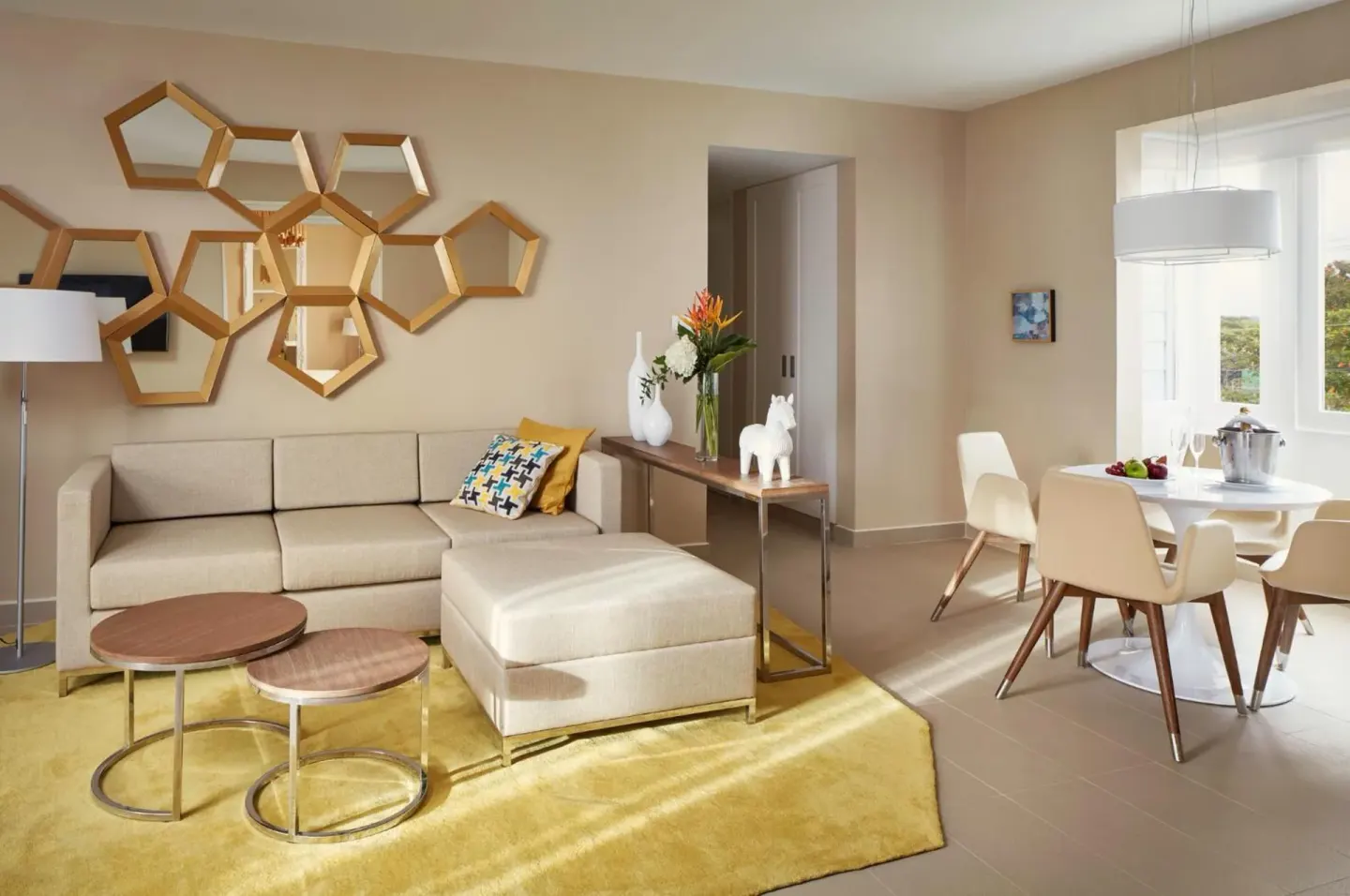 Living and dining area in a suite at Azul Beach Resort Negril with sofa, round table and wall mirrors.