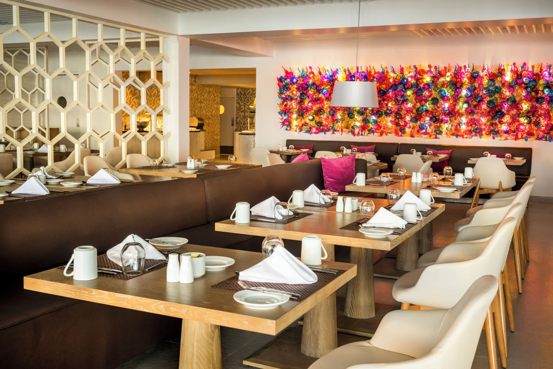 Restaurant dining area with set tables and colorful wall art at Azul Beach Resort Negril.