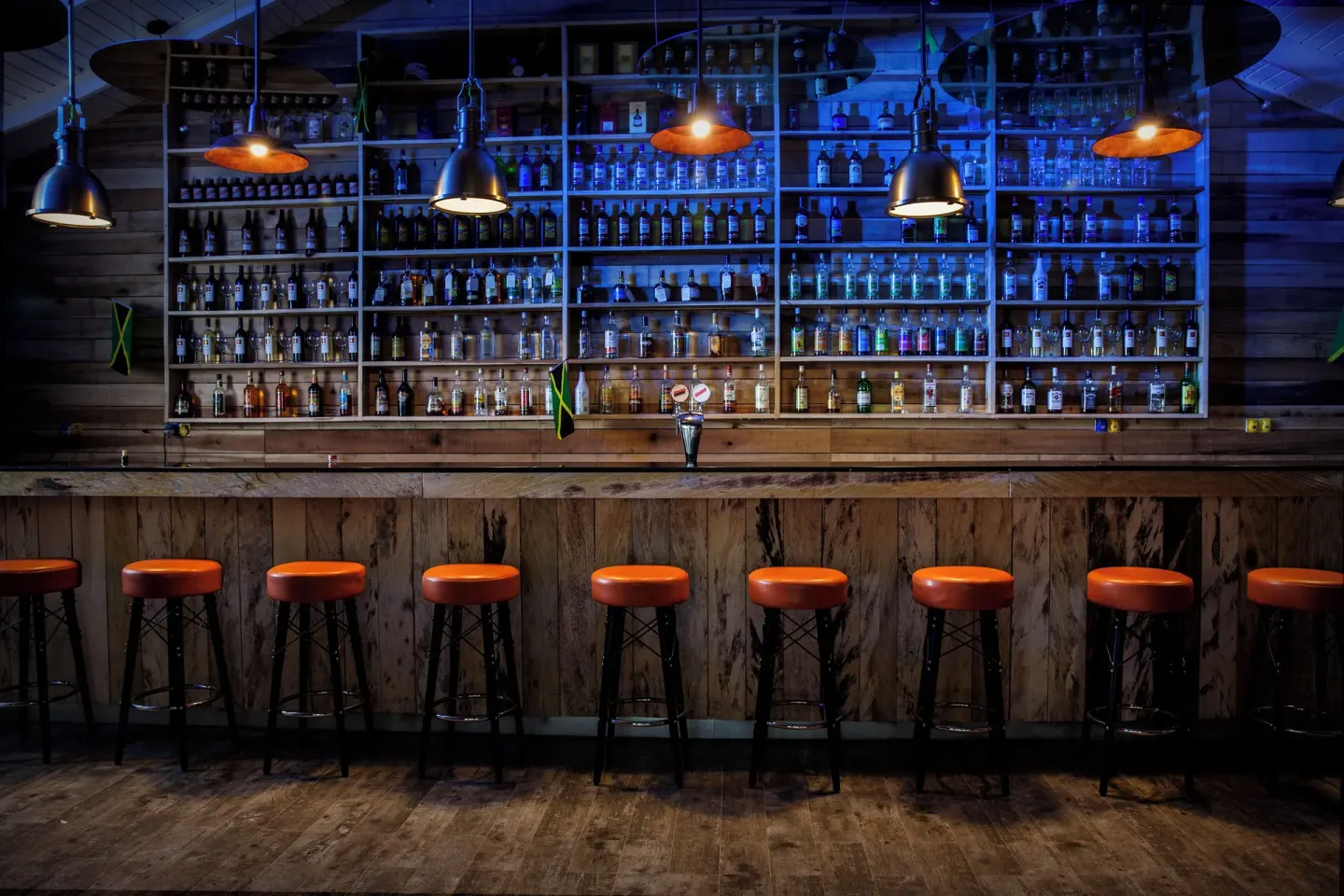 Wooden bar with orange stools and bottle shelves at Azul Beach Resort Negril.
