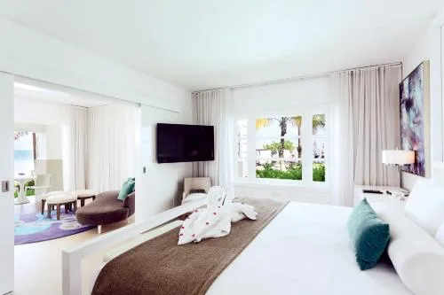 Beachfront Honeymoon Swim Up Suite king bed at Azul Beach Resort Negril with lounge area and garden view.