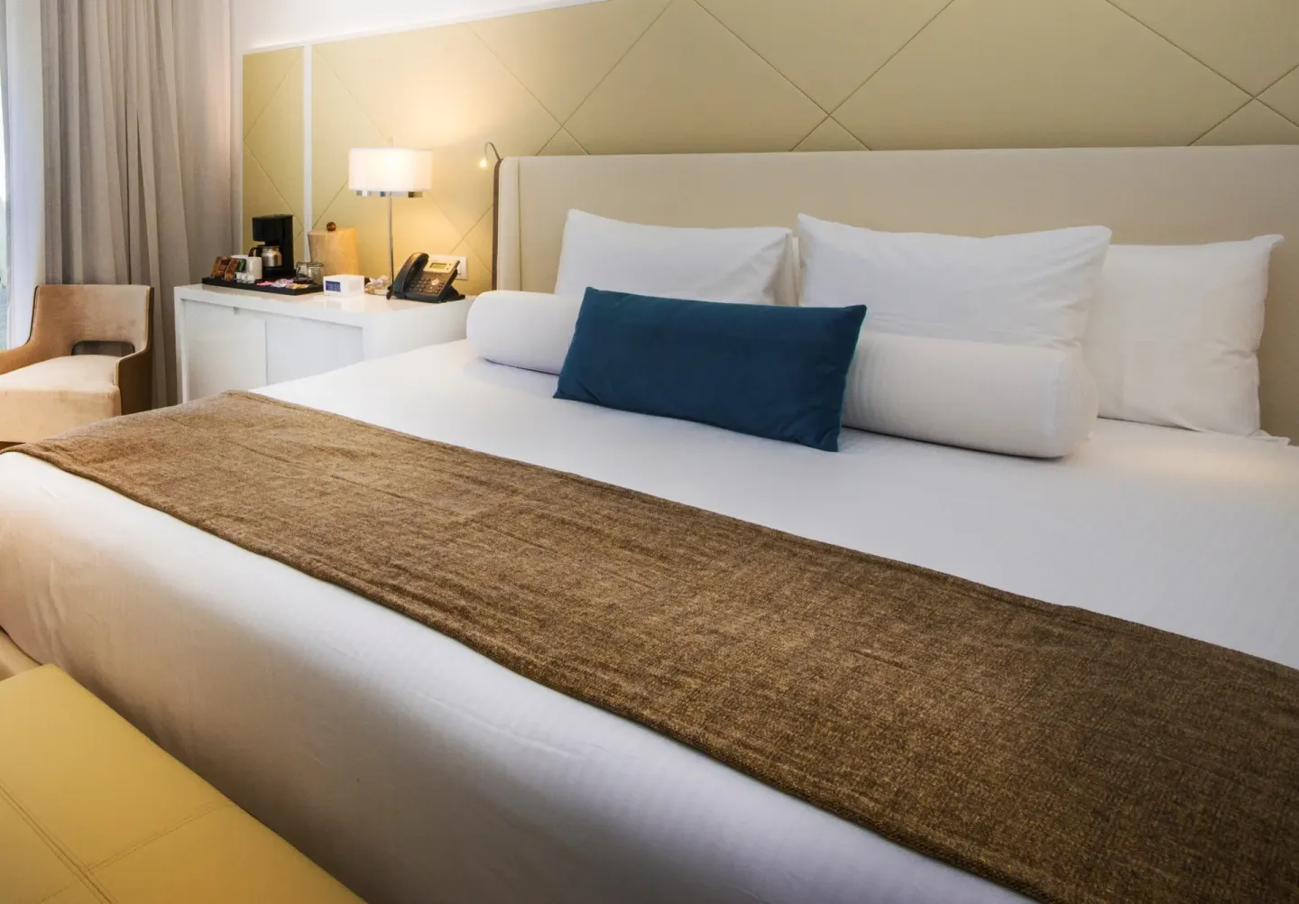 Deluxe Suite bed with white linens and teal pillow at Azul Beach Resort Negril.