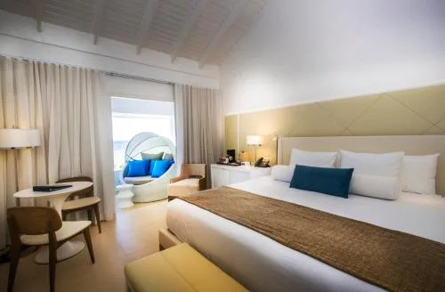 Deluxe Swim Up Room bedroom with king bed and seating at Azul Beach Resort Negril.