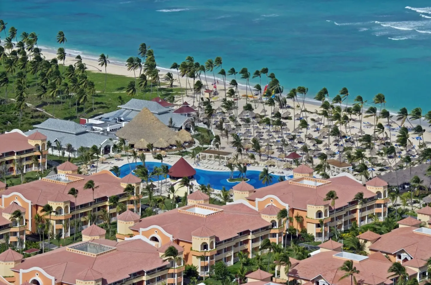 Aerial view of beachfront pools, palms, and guest buildings at Bahia Principe Escape Ambar.