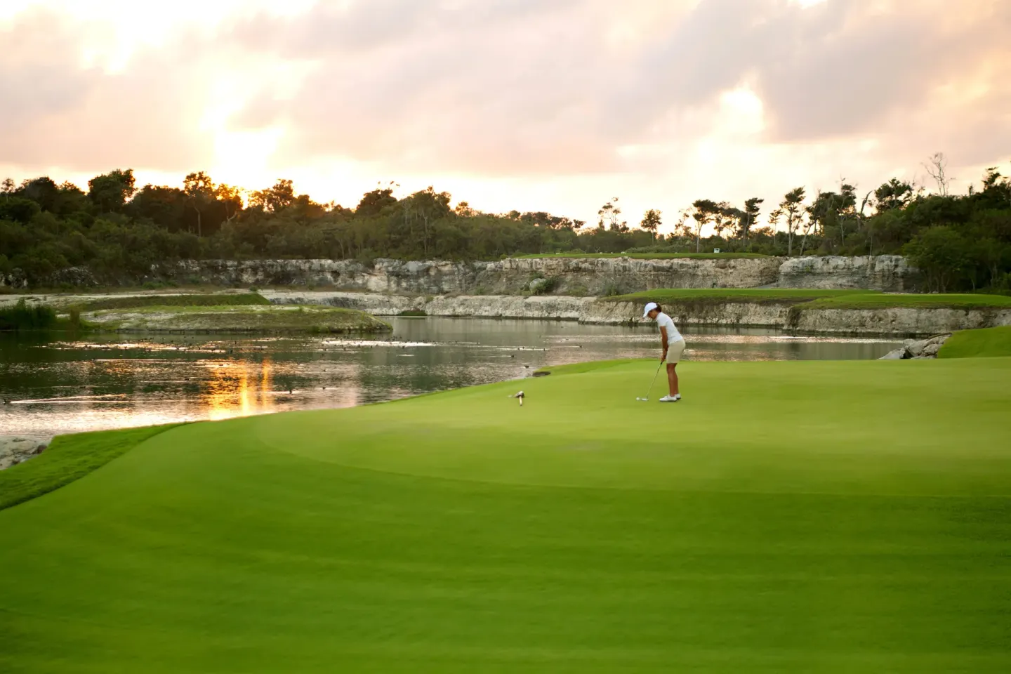 Golfer putting beside water at Bahia Principe Escape Ambar.