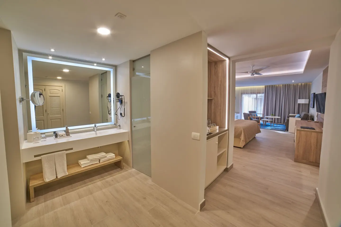 Bathroom vanity and bedroom sitting area in a guest room at Bahia Principe Escape Ambar.