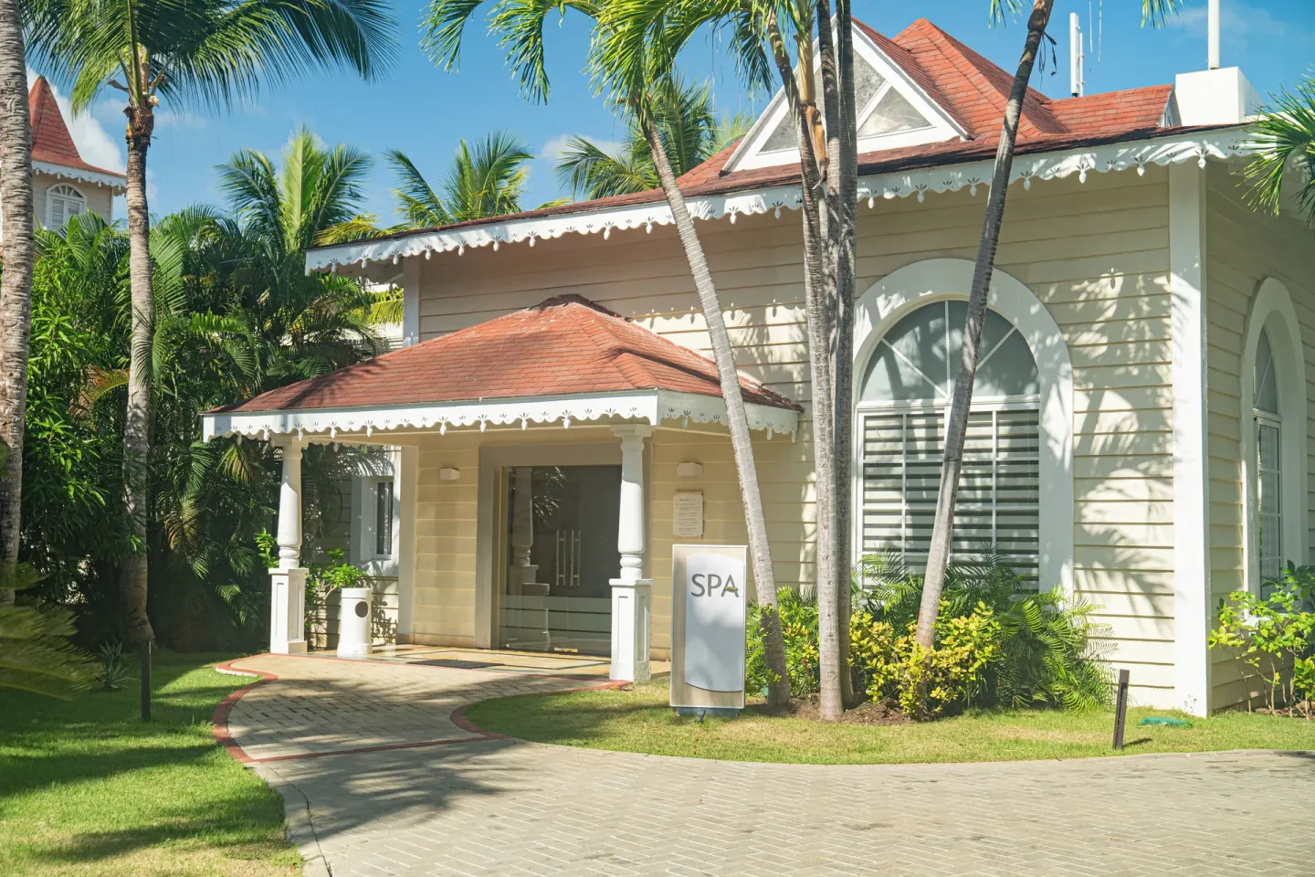 Spa building entrance with palms and a sign at Bahia Principe Escape Ambar.