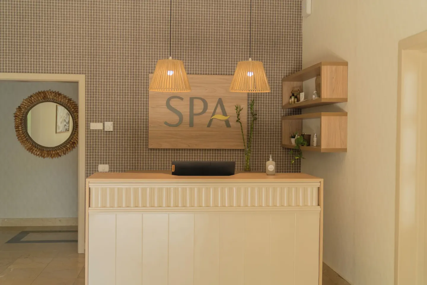 Spa reception desk with wood sign and pendant lights at Bahia Principe Escape Ambar.