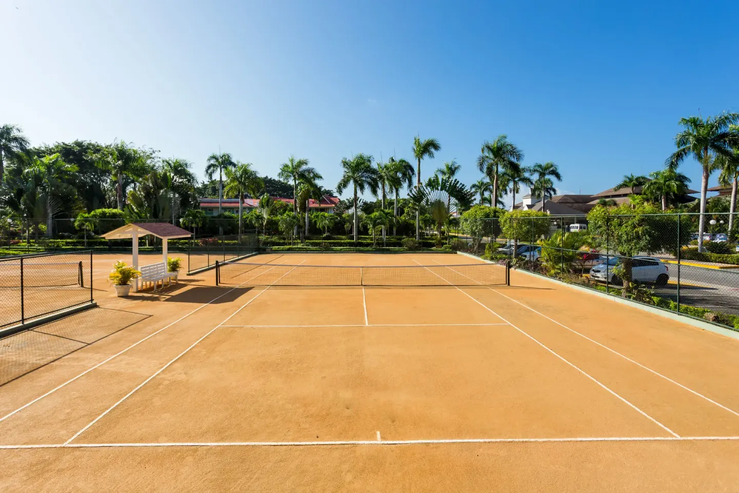 Tennis courts bordered by palms and fencing at Bahia Principe Escape Ambar.