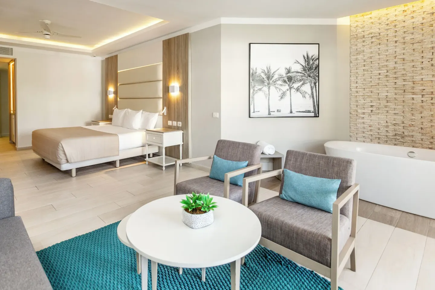 Corner Junior Suite lounge, king bed, and white soaking tub at Bahia Principe Escape Ambar.